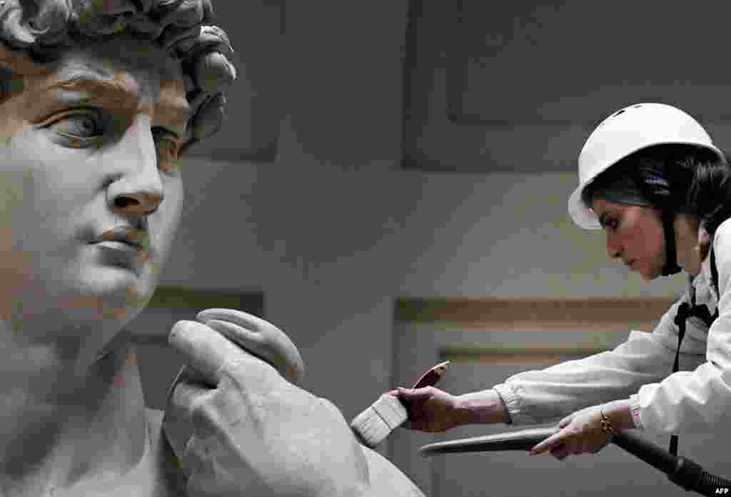 Italian restorer Eleonora Pucci cleans Michelangelo&#39;s statue of David using a backpack vacuum and synthetic fiber brush at the Galleria dell&#39;Accademia, in Florence.