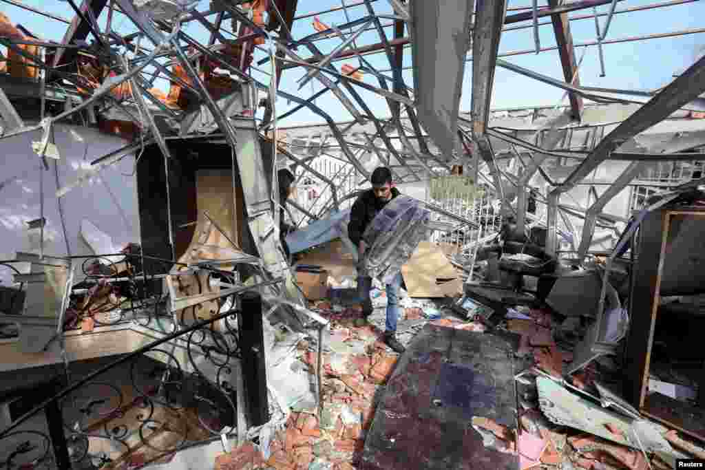 A man salvages items at a damaged site that was hit by an airstrike on Monday, after what Lebanon&#39;s state media said was a series of Israeli strikes around Ghaziyeh on Lebanon&#39;s coast 60 km north of the border with Israel.