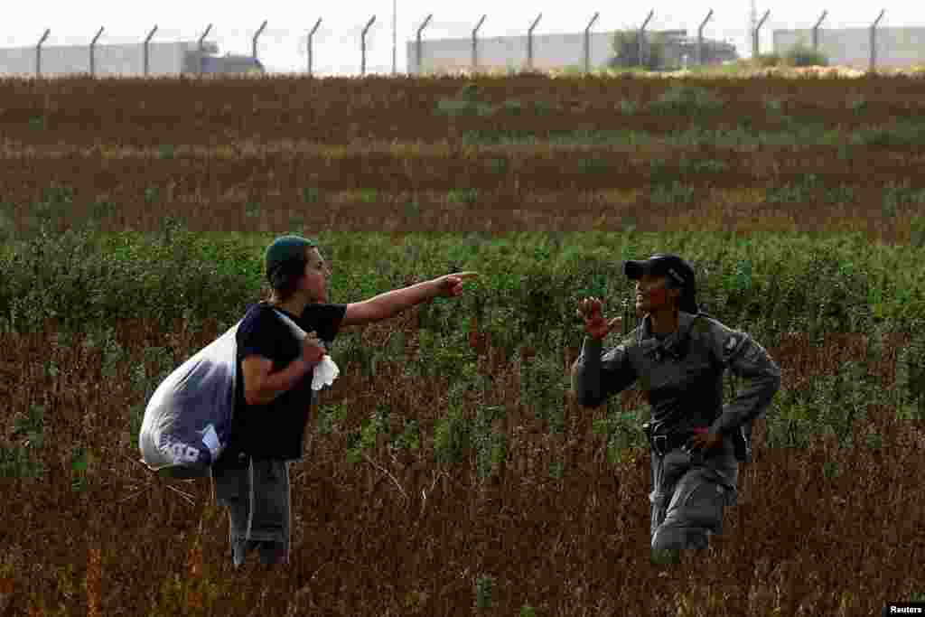 Israeli border police stop a man from heading to a protest against the delivery of humanitarian aid to Gaza and demand the immediate release of Israeli hostages kidnapped in the deadly October 7 attack, at the Kerem Shalom Crossing,&nbsp;as trucks waiting to enter Gaza from Egypt are seen in the background.
