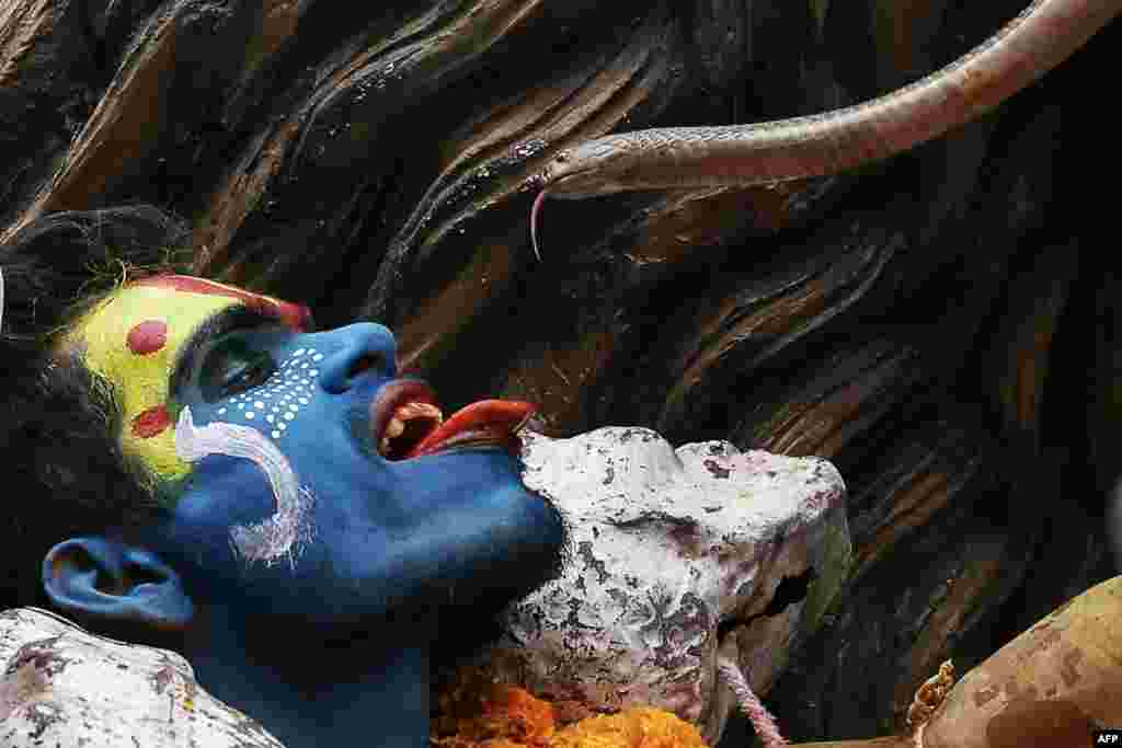 A Hindu devotee holds a snake during a religious procession on the occasion of &#39;Masaan&#39; or &#39;Bhasma&#39; Holi, which is celebrated with ashes of funeral pyres, in Varanasi, India.