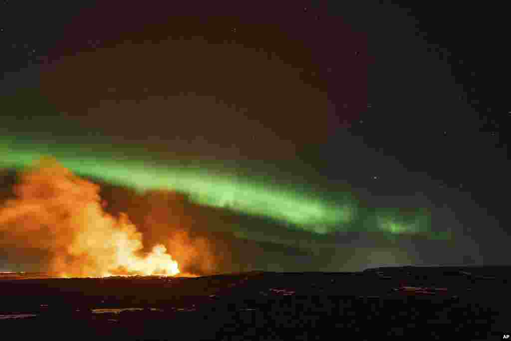 The eruption area of a volcano intersects with the northern lights dancing in the sky near the town of Grindavik, Iceland, March 28, 2024. 