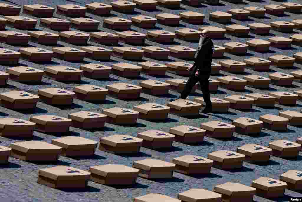 A person walks past some 1040 cardboard coffins, symbolizing the number of victims who lost their lives in a workplace last year, are placed in Piazza del Popolo in Rome, Italy, during the campaign &#39;Zero dead at work&#39; organized by the Italian Labor Union.