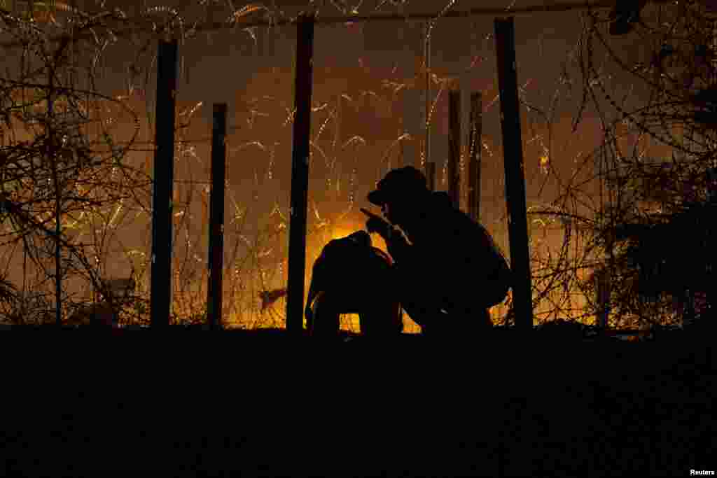 Men watch for U.S. authorities while shearing an opening through a razor wire-laden fence to enter into the United States from along the bank of the Rio Grande River, in El Paso, Texas, April 2, 2024. 