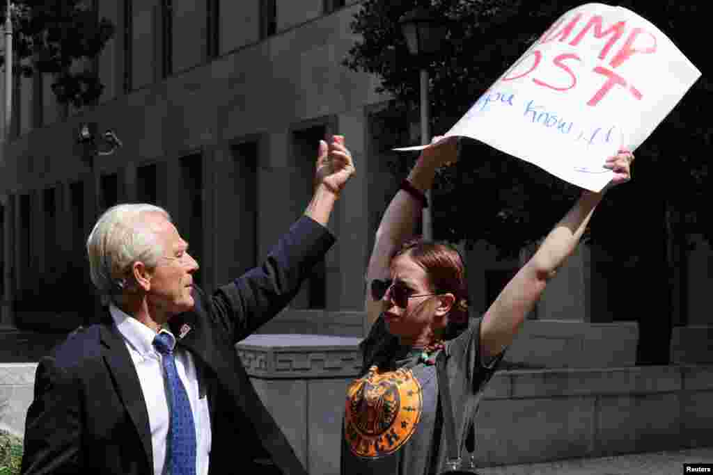 Peter Navarro, a White House economic adviser under former U.S. President Donald Trump, tries to grab a protester&#39;s sign while speaking to reporters after a pre-trial conference in an attempt to get contempt of Congress charges against him dismissed, at U.S. District Court in Washington.