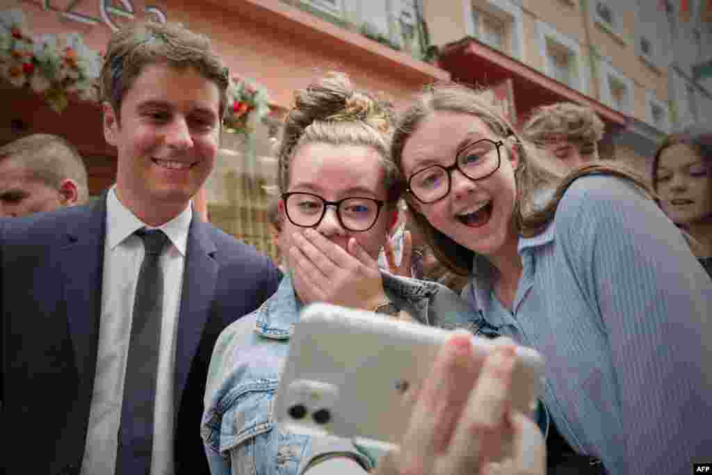 France&#39;s Prime Minister Gabriel Attal (C) poses for a selfie with young people during a campaign visit in Le Mans, northwestern France, ahead of the upcoming parliament elections.