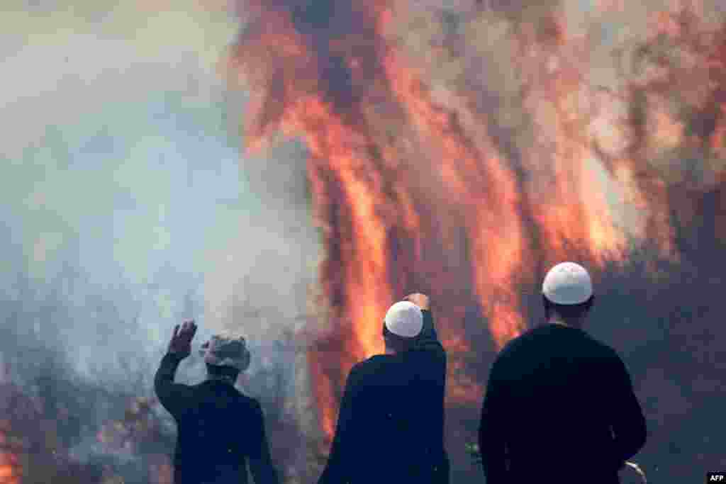 Local Druze men watch the flames burning a field after rockets launched from southern Lebanon landed on the Banias area in the Israel-annexed Golan Heights&nbsp;amid ongoing cross-border clashes between Israeli troops and Hezbollah fighters.