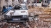 Cats sit in rubble front of a destroyed car at a damaged street after a 6.4-magnitude quake hit the Hatay province in southern Turkey, in Antakya, Feb. 21, 2023.