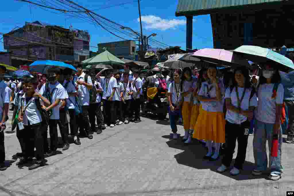 Students use umbrellas to protect themselves from the sun as they line up to wait for their classes outside their school in Manila, Philippines.&nbsp;More than100 schools in the capital shut their classrooms, as the tropical heat hit &quot;danger&quot; levels, education officials said.