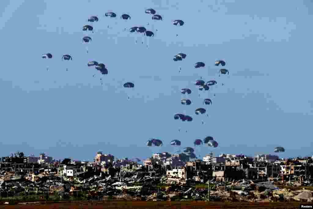 Packages fall towards northern Gaza, after being dropped from a military aircraft, amid the ongoing conflict between Israel and the Palestinian group Hamas, as seen from Israel&#39;s border with Gaza in southern Israel.