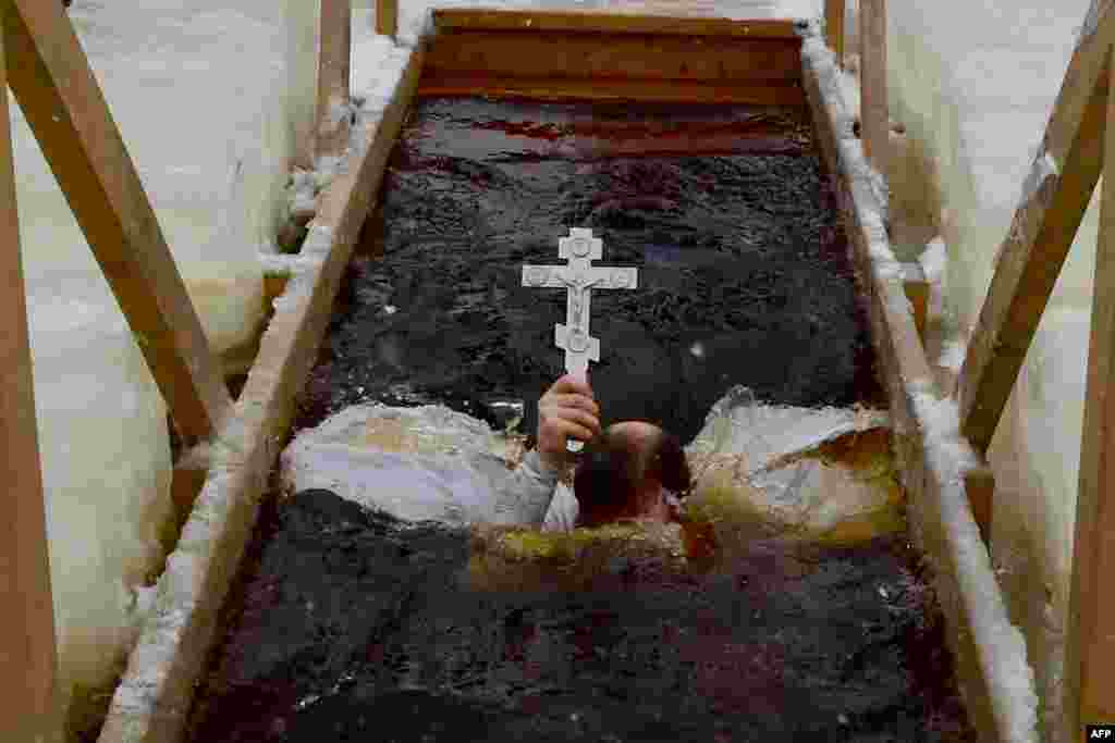 An Orthodox priest plunges into the icy waters of a lake during the celebration of the Epiphany holiday in the village of Orlino, Leningrad region, Russia. Among Orthodox Christians, the feast of Epiphany celebrates the day the spirit of God descended upon believers in the shape of a dove during Jesus Christ&#39;s baptism in the river Jordan.&nbsp;