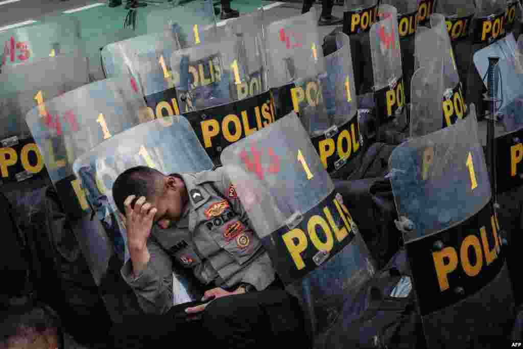 A policeman rests during a demonstration demanding the impeachment of Indonesia&#39;s President Joko Widodo, the rejection of the general election results and the removal of members of the General Election Commission, at the entrance of the parliament in Jakarta, March 5, 2024.