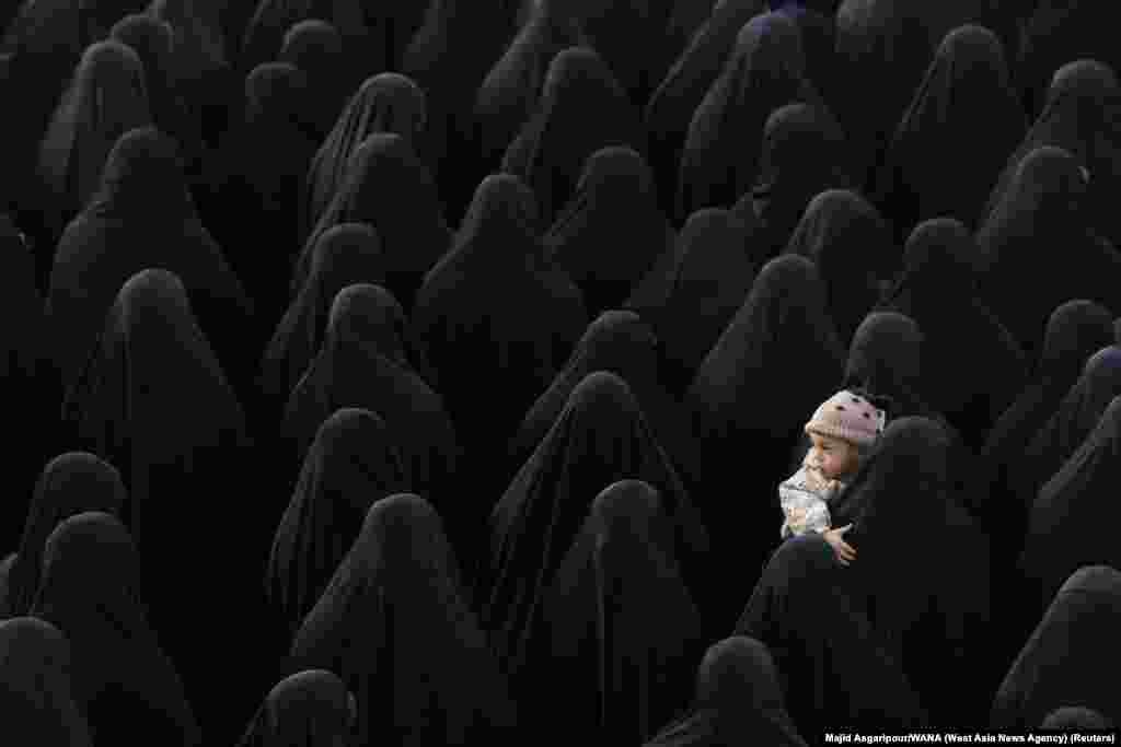 A woman holds a child as people gather for the funeral of Sadegh Omidzadeh and Mohammad-Amin Samadi, members of Iran&#39;s Islamic Revolution Guards Corps (IRGC), in Tehran, Iran.
