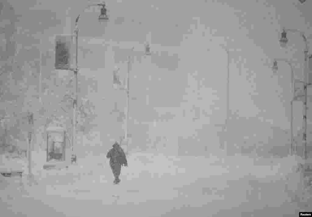 A person walks across the empty street during the first winter storm of 2024 which is expected to bring heavy snowfall across the northeast United States, in Worcester, Massachusetts, Jan. 7, 2024. 