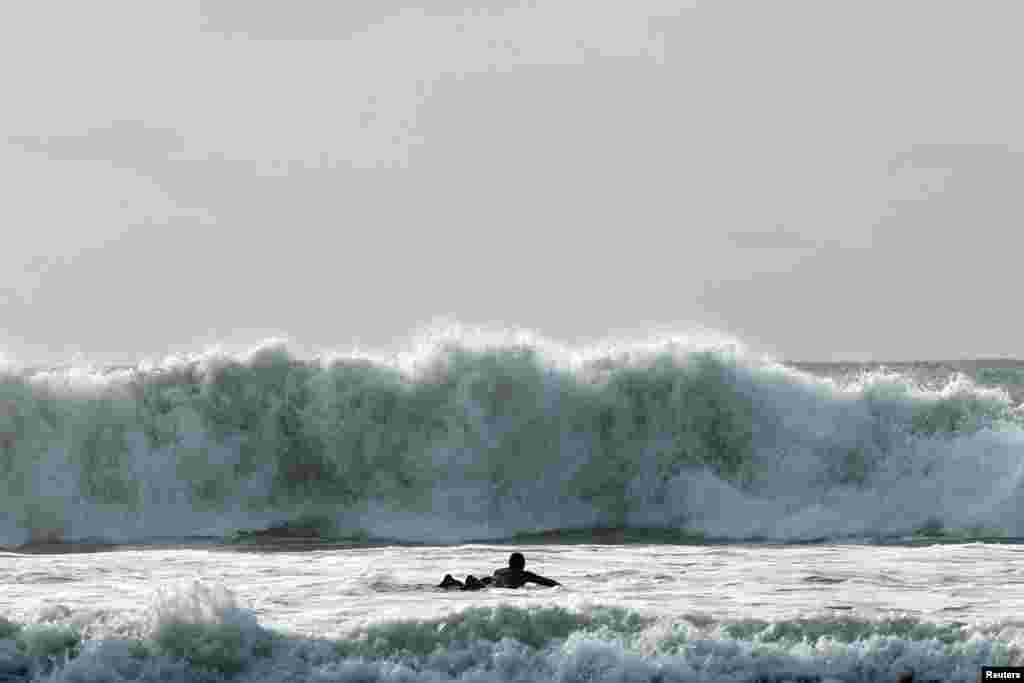A surfer tries to navigate through a rough sea during Storm Ciaran, in Tramore, Ireland.