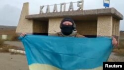 一名乌克兰士兵在南部赫尔松地区的一个村庄里展示乌克兰国旗。（2022年11月11日）