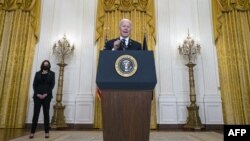 Presidenti Biden duke njoftuar arritjen e 100 milionë injektimeve të vaksinës, ndërsa në sfond qëndron Nënpresidentja Harris (Dhoma Lindore e Shtëpisë së Bardhë, 18 mars 2021)