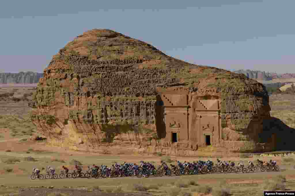 The peloton passes by ancient Nabataean carved tombs as it crosses the archaeological site of al-Hijr (Hegra), during the first stage of the Saudi Tour from Winter Park near Saudi Arabia&#39;s northwestern city of al-Ula.
