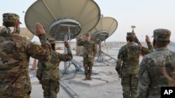 In this photo released by the U.S. Air Force, Col. Todd Benson, the U.S. Air Force Central Command director of space forces, center, leads airmen through their enlistment ceremony as they became members of the Space Force at Al-Udeid Air Base, Qatar…
