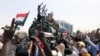 Los oficiales y manifestantes militares sudaneses montan sobre un camión cisterna militar para protestar contra el anuncio del ejército de que el presidente Omar al-Bashir sería reemplazado por un consejo de transición liderado por militares.