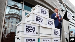 Jason Savage, executive director of the Maine GOP, speaks about efforts to repeal ranked-choice voting while standing next to boxes containing signed petitions near the State House, Monday, June 15, 2020, in Augusta, Maine. The state Republican…