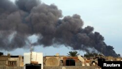 De la fumée monte d’une usine après une frappe des forces loyales au maréchal Khalifa Haftar à Benghazi, Libye, 22 octobre 2014.