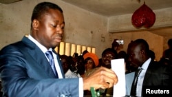 Le président du Togo Faure Gnassingbe (G) place son vote dans l'urne à Lome, le 25 juillet 2013.