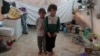 Des frères et sœurs syriens, déplacés de l'est de la province d'Idlib, posent pour une photo dans une tente du camp d'Atmeh en Syrie, près de la frontière turque, le 19 juin 2020.