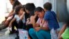 ARCHIVO - En esta foto de archivo del 16 de julio de 2019, migrantes esperan en un centro migratorio en el Puente Internacional 1 en Nuevo Laredo, México.