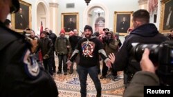 Një ndër ndjekësit e teorisë QAnon duke u përballur me policinë brenda godinës së Kapitolit të Shteteve të Bashkuara (Uashington, 6 janar 2021)