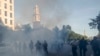 Tear gas floats in the air as a line of police move demonstrators away from St. John's Church across Lafayette Park from the White House, as they gather to protest the death of George Floyd, Monday, June 1, 2020, in Washington. Floyd died after…