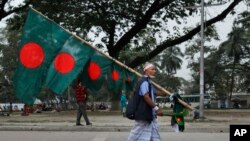 ঢাকায় বিজয় দিবসের আগে একজন বিক্রেতা বাংলাদেশের পতাকা নিয়ে। ১৪ ডিসেম্বর, ২০১৫। এপি ফাইল ছবি।