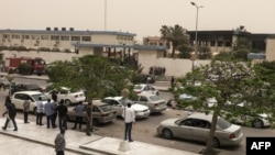 Des passants se rassemblent devant le bâtiment électoral visé par un attentat, à Tripoli, le 2 mai 2018.