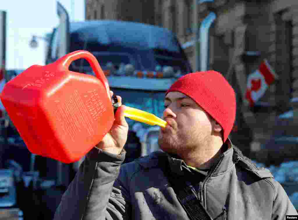 A person pretends to drink from a fuel can after police said they will be targeting the truckers&#39; fuel supply, Feb. 7, 2022. Truckers and their supporters continued to protest COVID-19 vaccine mandates, in Ottawa, Ontario, Canada.