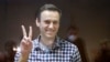 Russian opposition leader Alexei Navalny gestures as he stands in a cage in the Babuskinsky District Court in Moscow, Russia, Saturday, Feb. 20, 2021. Two trials against Navalny will be held: Moscow City Court will consider an appeal against his…