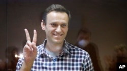 Russian opposition leader Alexei Navalny gestures as he stands in a cage in the Babuskinsky District Court in Moscow, Russia, Saturday, Feb. 20, 2021. Two trials against Navalny will be held: Moscow City Court will consider an appeal against his…