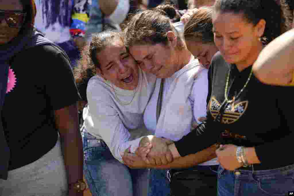 A sister of miner Santiago Mora, left, cries with other relatives as he is buried at the cemetery in La Paragua, Bolivar state, Venezuela.&nbsp;The collapse of an illegally operated open-pit gold mine in central Venezuela killed at least 14 people and injured several more, state authorities said, as some other officials reported an undetermined number of people could be trapped.