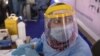 Un agent de santé portant un équipement de protection se prépare à prélever des échantillons au Caire, le 17 juin 2020.