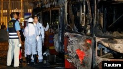 La policía de Perú e investigadores trabajan junto a un autobús calcinado en una calle de Lima, Perú, el 31 de marzo de 2019.