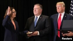 Gina Haspel jure sur la Bible tenue par Mike Pompeo, le secrétaire d'état. Elle est la nouvelle directrice de la CIA. A droite, le président américain Donald Trump assiste à la cérémonie à Langley, le siege de la CIA, le 21 mai 2018. 