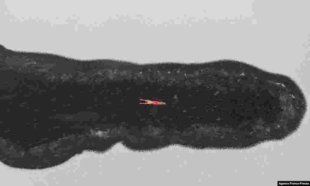 A winter swimming enthusiast swims in a partly frozen lake during snowfall at a park in Shenyang, in northeastern China&#39;s Liaoning province.